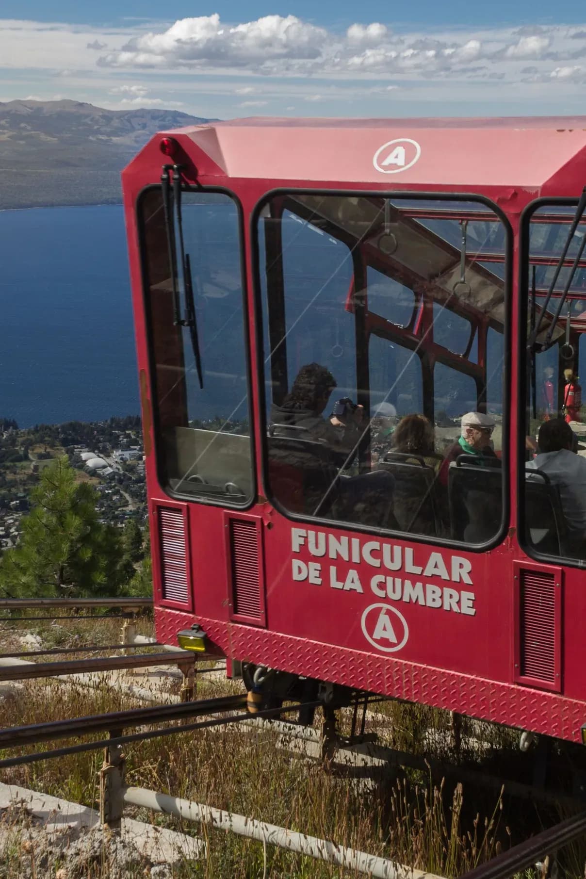 Primer plano del funicular de la cumbre con personas dentro mientras desciende con el lago Nahuel Huapi de fondo