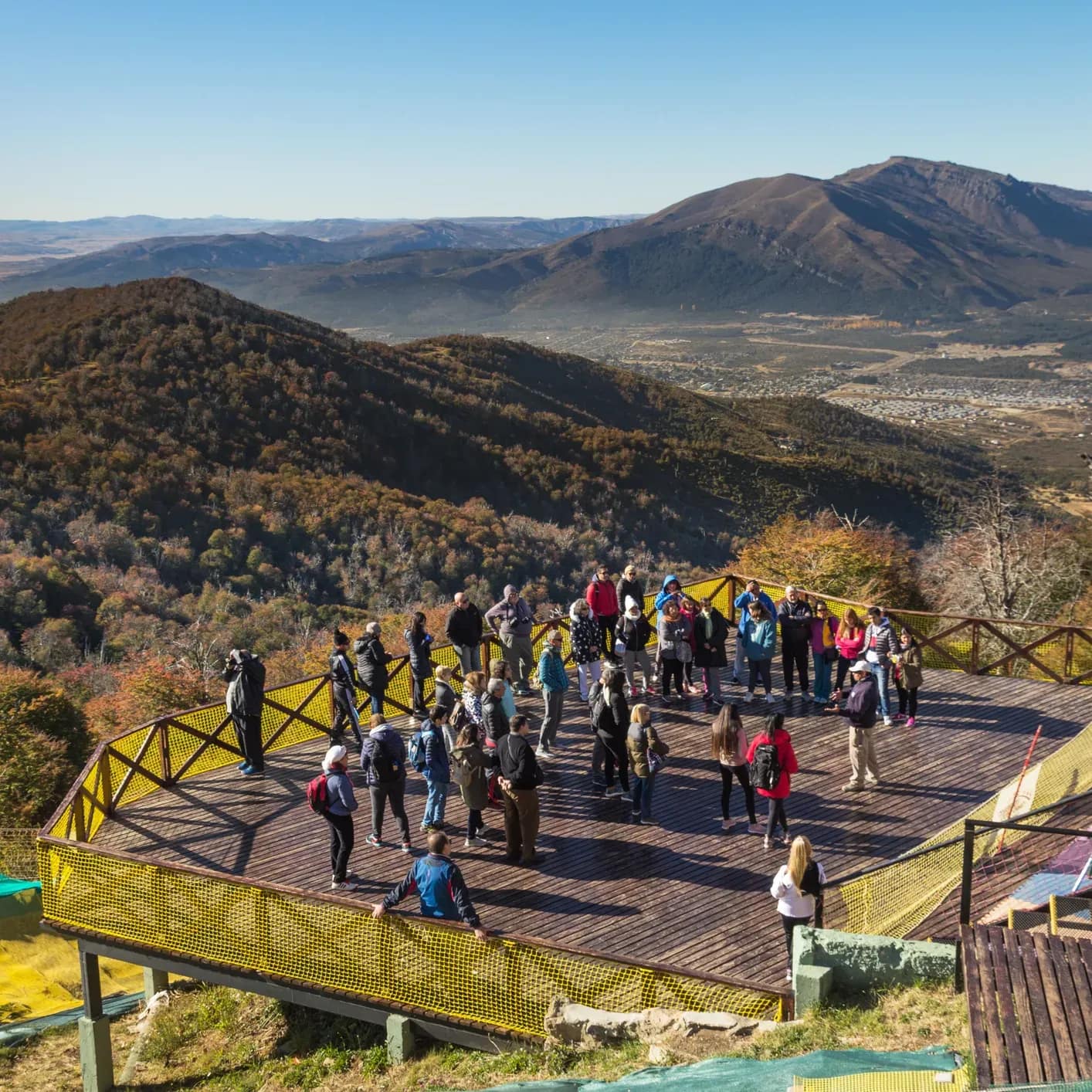 Deck panorámico con personas admirando el paisaje de montañas
