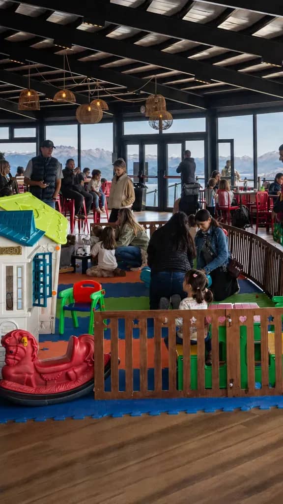 Patio de comidas con personas comiendo y admirando el paisaje panoramico del lago Nahuel Huapi
